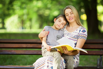 Mother and son sitting on a bench in park