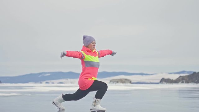 Girl is training practice yoga in winter. Woman is do stretching and meditation on ice in nature. Athlete practices yoga on beautiful with cracks ice. Woman do sport fitness in outdoor. Background