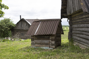 A small old wooden well at the wall of a village house