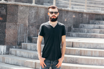 Obraz premium Stylish man male model with beard wearing black blank t-shirt with space for your logo or design in casual urban style