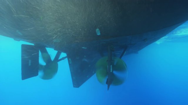 Underwater shot of big boat propeller spinning as they move across the ocean.