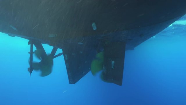 Underwater shot of big boat propeller spinning and stops.