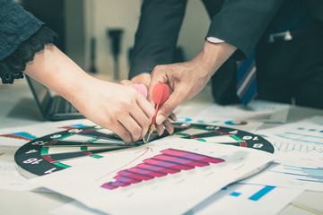 Fototapeta premium Strategy and target concept,close up hands of business people group put darts on goal of board and planning to achievement in meeting room