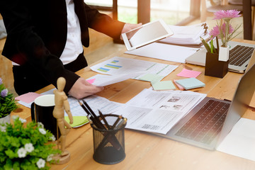 Young attractive businesswoman working on a paperwork, tablet in her office