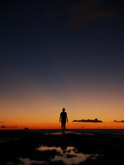 Fototapeta na wymiar woman silhouette walking on pier into a colorful sunset