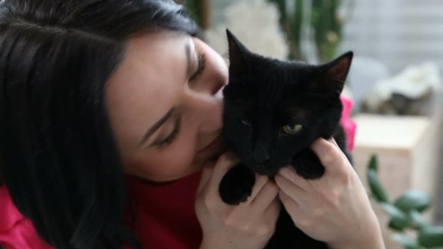 love for pets. beautiful dark-haired girl with a black cat is relaxing at home in the bed room
