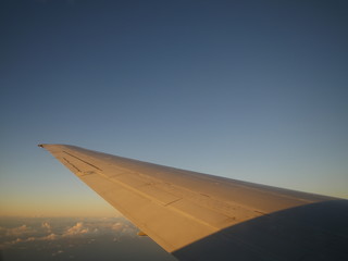 Fototapeta na wymiar airplane wing flying in the air during golden hour above the clouds