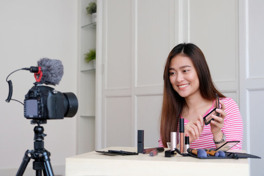 Young asian woman beauty blogger showing how to make up video tutorial, vlog concept, people and technology communication
