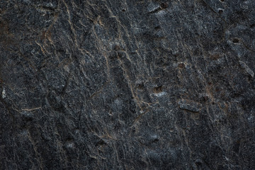 Close-up of a rough dark stone texture, perfect for backgrounds, design projects, and nature-themed elements.