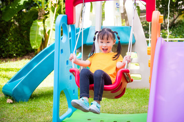 Fototapeta na wymiar Little asian girl playing swing chair at school playground