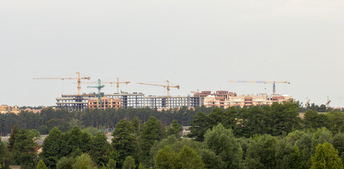 Fototapeta na wymiar tower crane against the blue sky, the process of building a multi-storey building