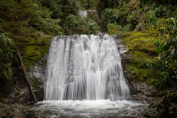 Fototapeta na wymiar Waterfall in a forest with mossy rocks