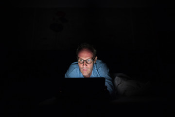 Mature Scandinavian man using digital tablet in dark room