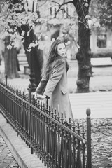 lonely girl in the park. Young woman in camel coat walks in autumn park.