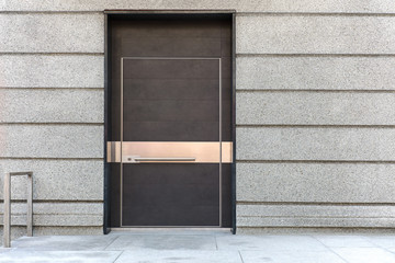 Obraz na płótnie Canvas closed brown metal door on grey stone wall of building facade 