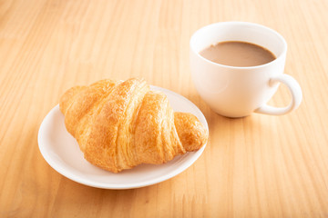 Coffee and croissant on wooden background