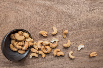 Raw cashew nuts in bowl on textured wooden background, table top view
