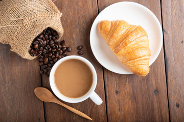 Coffee and croissant on wooden background