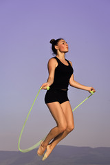 exercises with a skipping rope. Workout of girl on blue sky background.