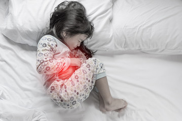 a little girl in her bed has a stomachache