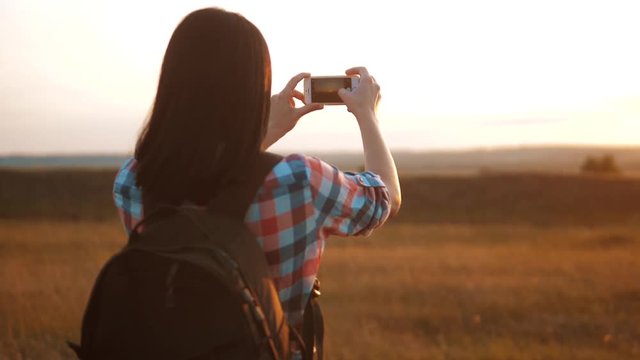 Hipster hiker silhouette girl is shooting video of beautiful nature sundown on cell telephone smartphone slow motion video. Female tourist is taking photo with mobile phone camera. girl lifestyle