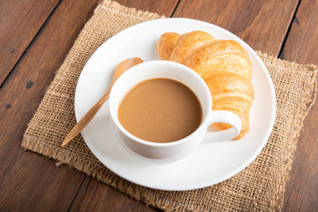 Coffee and croissant on wooden background