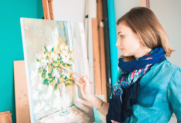 portrait of a girl painter with a palette of colorful paintings in an art studio. Thoughtful artist,