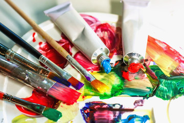 Used palette of the artist with mixed colors of acrylic paints close-up as an artistic background.