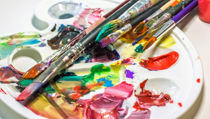 Obraz premium Art brushes and paints for painting on the used palette with paints close-up.
