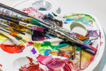 Fototapeta premium Palette of the artist with oil paints and brushes for drawing. close-up as an artistic background.