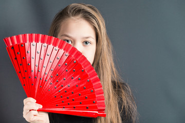 Beautiful girl with a red fan from the heat