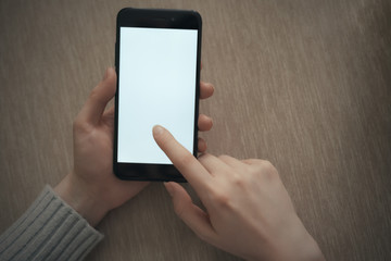 close-up hand holding phone white screen over work table