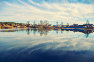 Naklejka premium Spring weather. Water overflowing, spring flood landscape, pond and house in the background, Eastern Europe rural landscape, skyline and clouds
