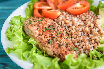 Grilled chicken breast with buckwheat porridge, tomatoes and avocado on blue wooden background. Diet nutrition, healthy food for lunch.