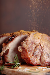 Oven-baked pork with rosemary and spices on a wooden table.