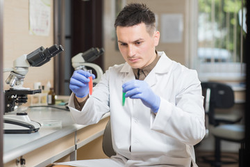Naklejka na ściany i meble A young man scientist or doctor working with test tubes in lab