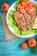 Grilled chicken breast with buckwheat porridge, tomatoes and avocado on blue wooden background. Diet nutrition, healthy food for lunch.