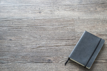 Mockup close diary book with blank black leather cover template paper texture on dark grey wood table