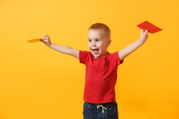 Little cute kid baby boy in red t-shirt holding in hand yellow and red soccer referee cards for retire from field isolated on yellow background. Kids sport family leisure lifestyle concept. Copy space