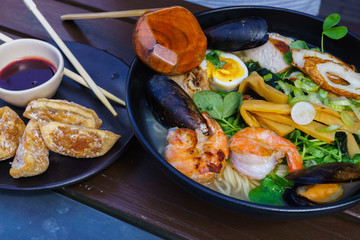 Noodle soup with seafood including mussels, prawns, squids, eggs, vegetables.