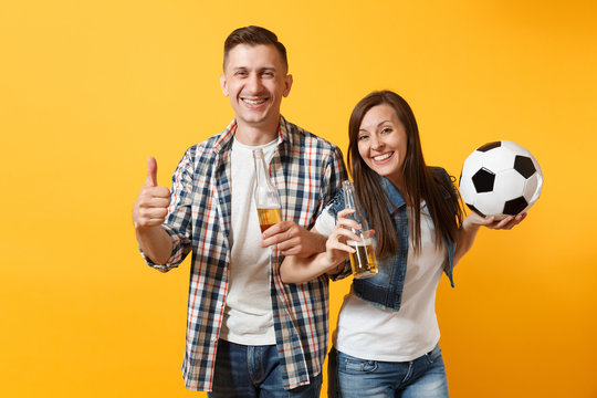 Young happy cheerful couple supporter, woman man, football fans cheer up support team, holding beer bottle, soccer ball isolated on yellow background. Sport, family leisure, people lifestyle concept.