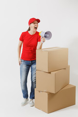 Full length portrait of delivery woman in red cap, t-shirt isolated on white background. Female courier screaming in megaphone near empty cardboard boxes. Receiving package. Copy space advertisement.