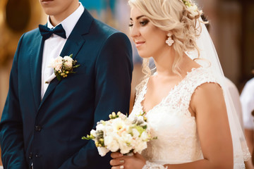 Wedding bouquet with delicate pink, beige, white flowers with green leaves in the hands of the...