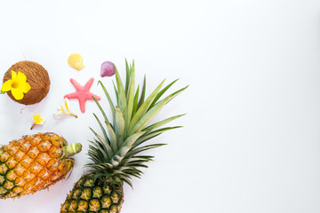 Tropical fruit composition with pineapples, coconut, flowers, shells and starfish. Summer vacation background concept. top view,flat lay