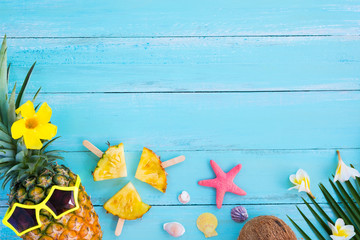 Hipster pineapple fashion with tropical fruit, seashells, starfish and flowers on wood plank blue color. Summer vacation background concept.