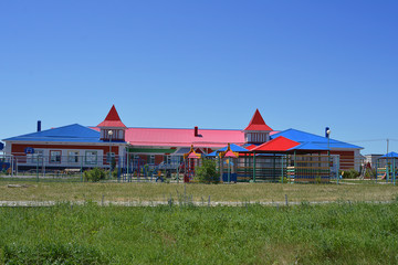 Complex of buildings of a kindergarten with multi-colored roofs on a summer day.