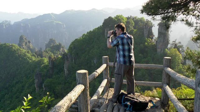 Professional photographer taking pictures of mountain landscape at sunset.  Zhangjiajie Forest Park, China