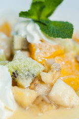 Close-up - ice cream with fruit salad with banana, orange and kiwi and fresh bunch of mint. Dessert from the restaurant