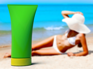 Woman in a swimsuit against the background of the blue sea and bottle of sunblock cream or lotion