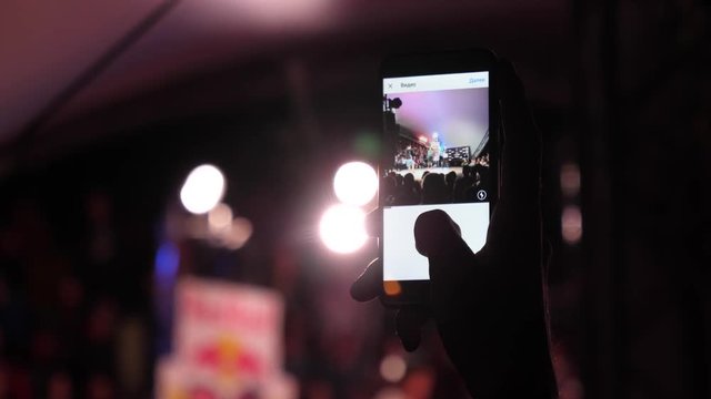 Holding shooting video or take picture on mobile smartphone camera during public event at night